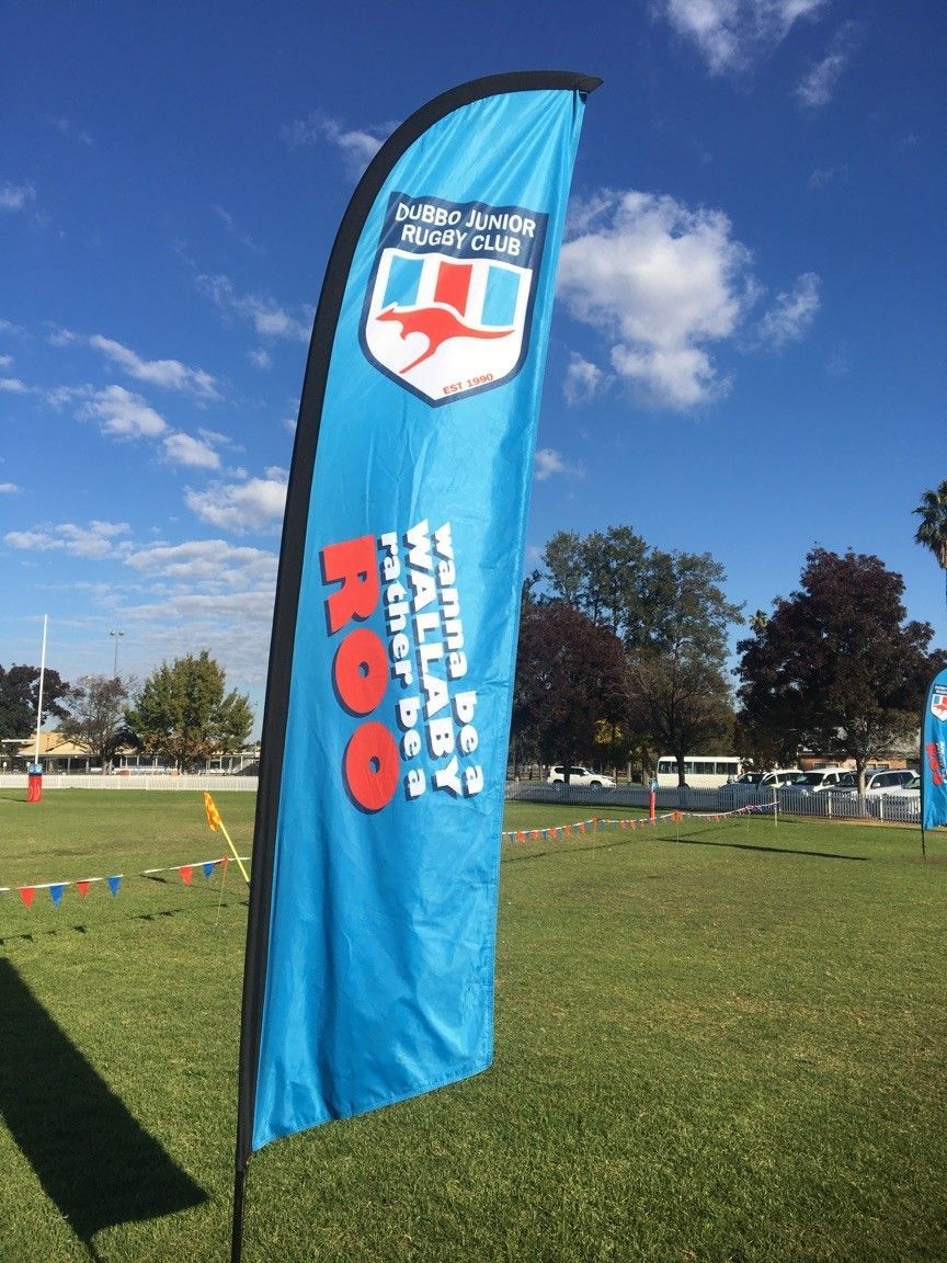 A blue feather flag in a grassy field with a kangaroo logo and the text 