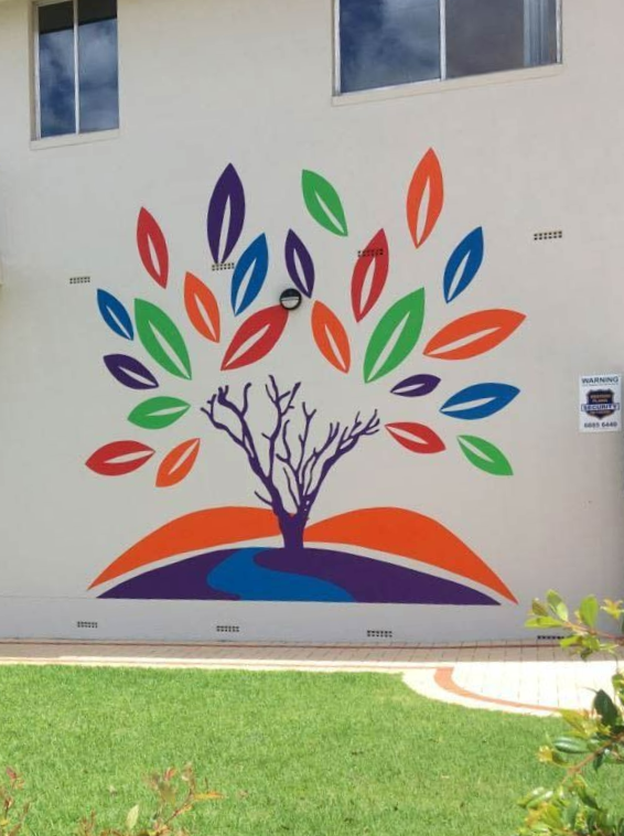 Mural of a colorful tree with leaves and a stream on a white wall, over grass — Signvision In Dubbo, NSW