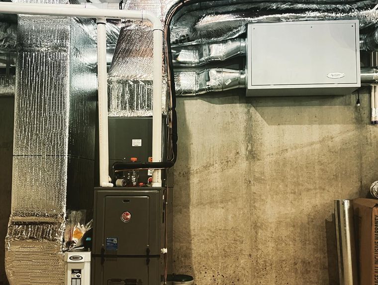 Basement utility room with HVAC units, exposed ductwork, and a concrete wall Basement utility room with HVAC units, exposed ductwork, and a concrete wall