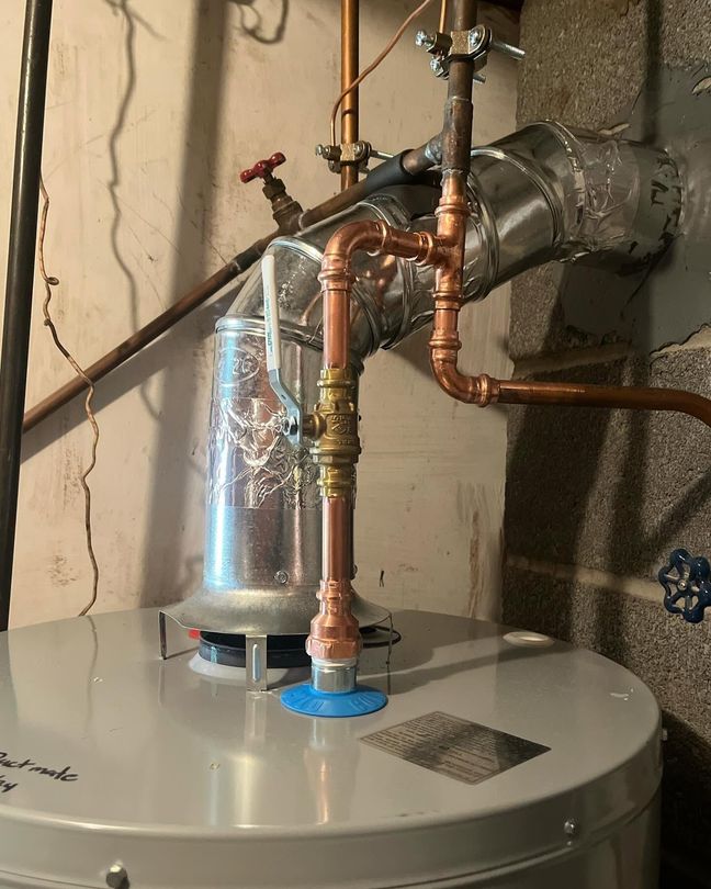 Water heater with copper plumbing and vent pipe in a basement utility area Water heater with copper plumbing and vent pipe in a basement utility area