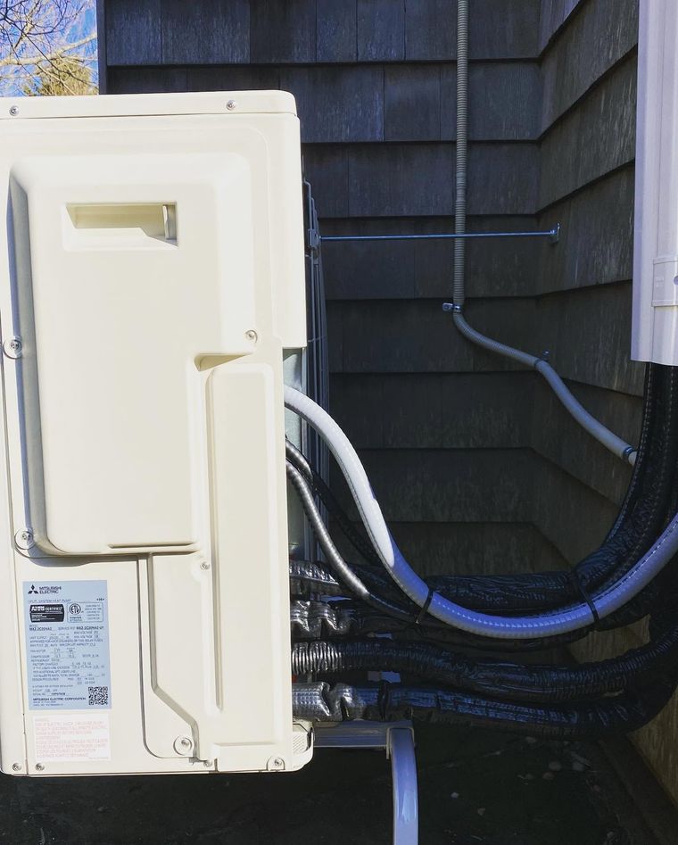 Exterior utility panel with white cover and bundled cables beside dark house siding Exterior utility panel with white cover and bundled cables beside dark house siding