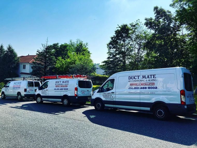 White service vans parked on gravel near trees and a building, with “DUCT MATE” visible on one van. White service vans parked on gravel near trees and a building, with “DUCT MATE” visible on one van.