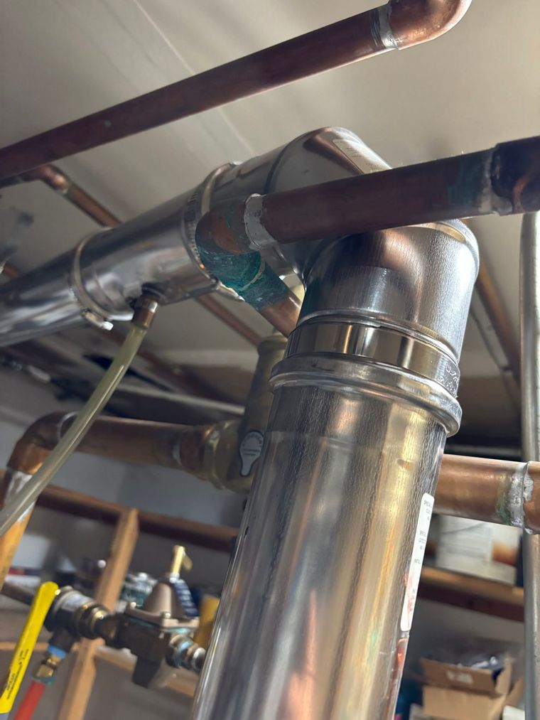 Close-up of shiny metal HVAC ductwork and pipes in a basement ceiling Close-up of shiny metal HVAC ductwork and pipes in a basement ceiling