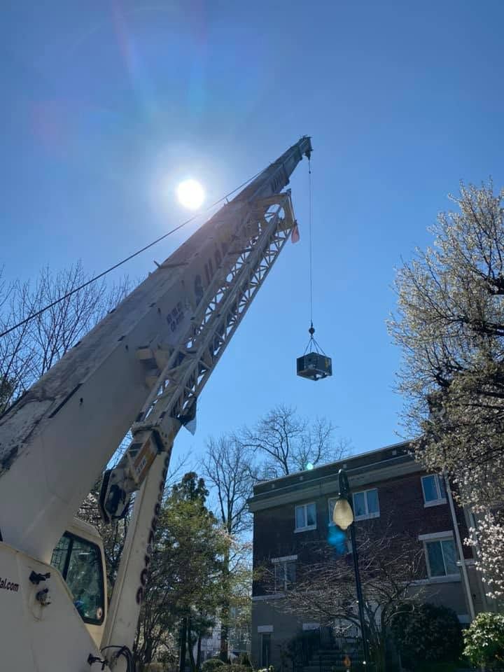 Crane lifting a load beside a brick house under a bright blue sky Crane lifting a load beside a brick house under a bright blue sky