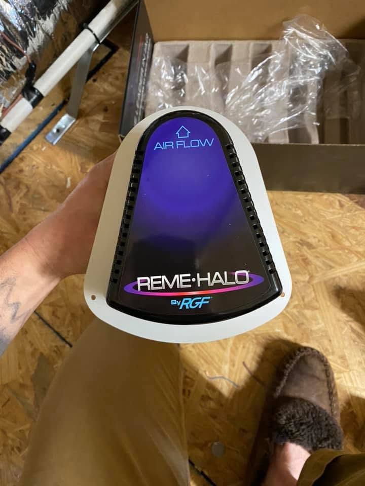 Hand holding a purple and black RemE-Halo air purifier box in a storage area Hand holding a purple and black RemE-Halo air purifier box in a storage area