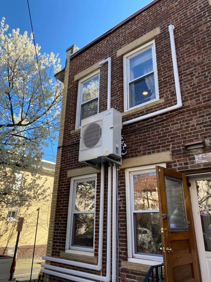 Brick townhouse exterior with a wall-mounted air conditioner and open wooden door Brick townhouse exterior with a wall-mounted air conditioner and open wooden door