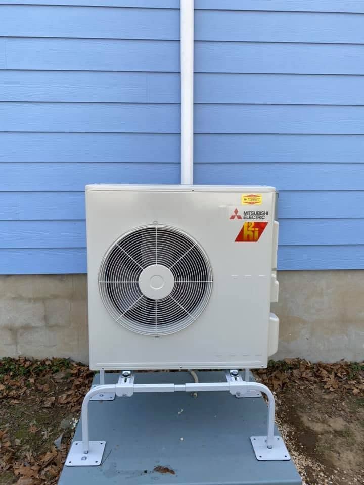 Outdoor wall-mounted air conditioner unit against a light blue exterior wall, with a metal support frame on concrete. Outdoor wall-mounted air conditioner unit against a light blue exterior wall, with a metal support frame on concrete.