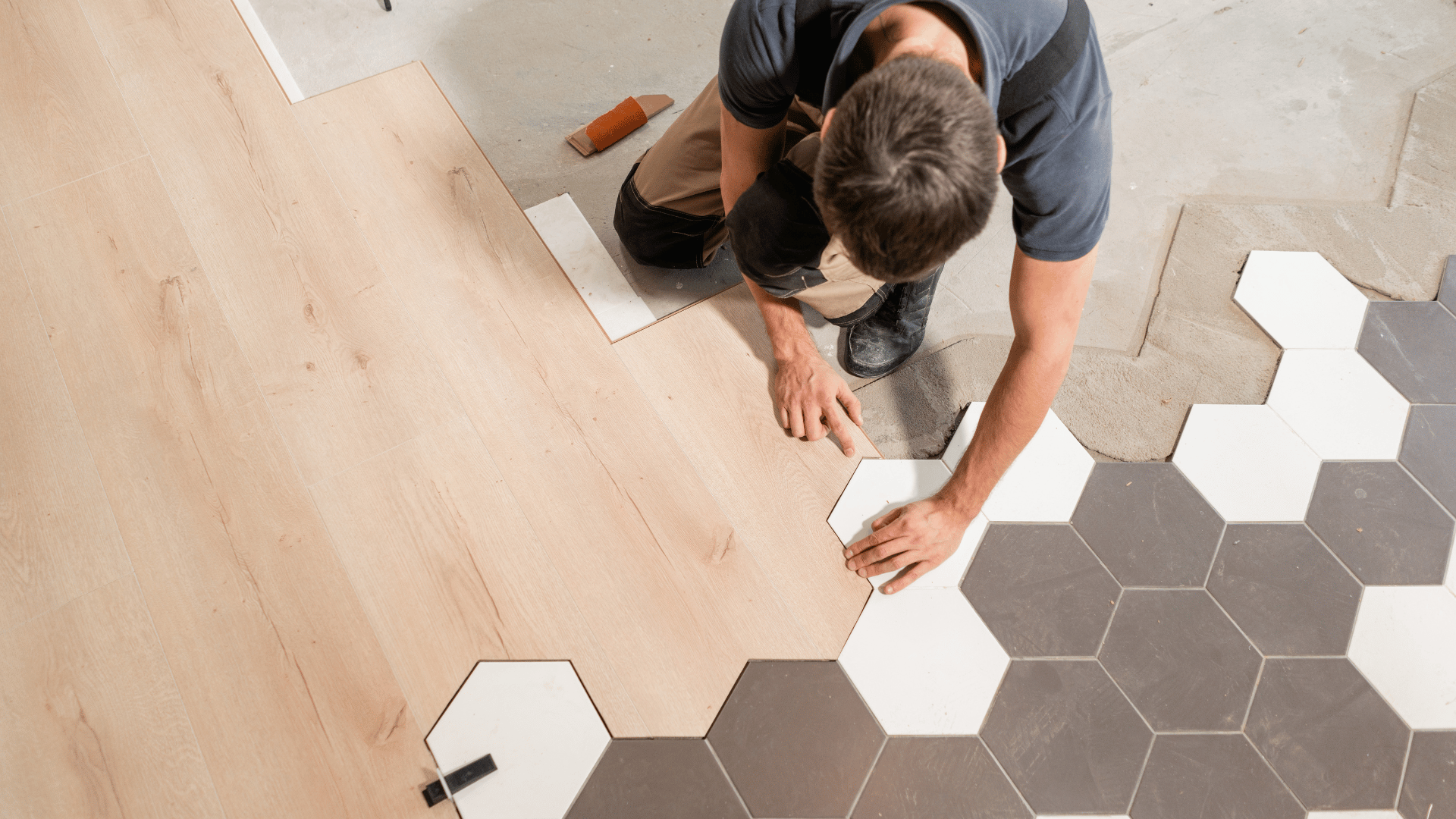 A man is installing a wooden floor with hexagonal tiles.