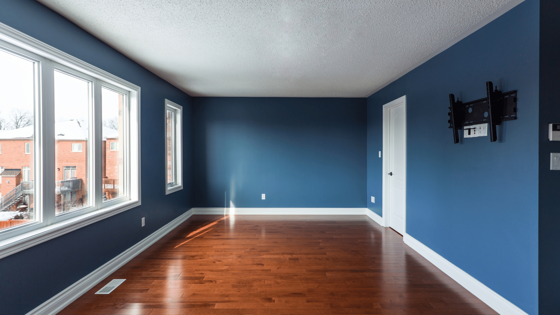 An empty living room with blue walls and hardwood floors.
