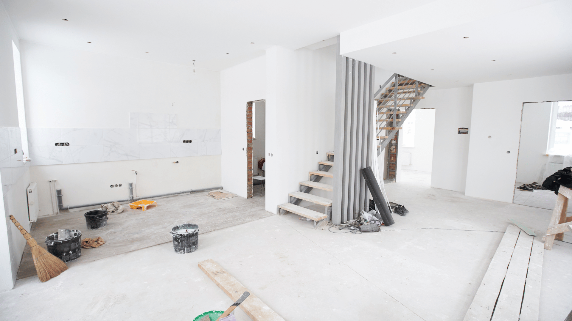 A man is working on a staircase in a house under construction.