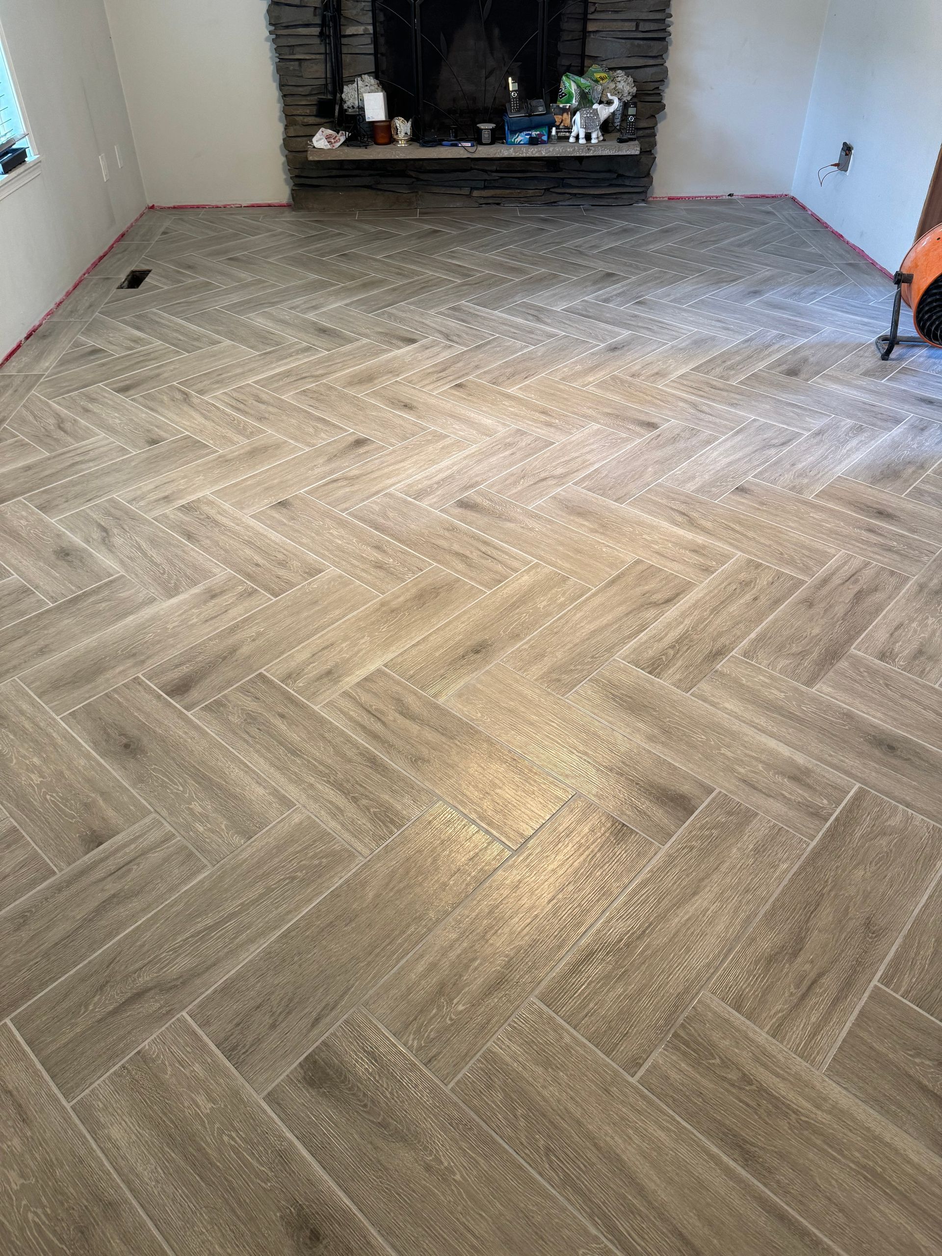 Herringbone tile floor in a living room, leading to a fireplace.