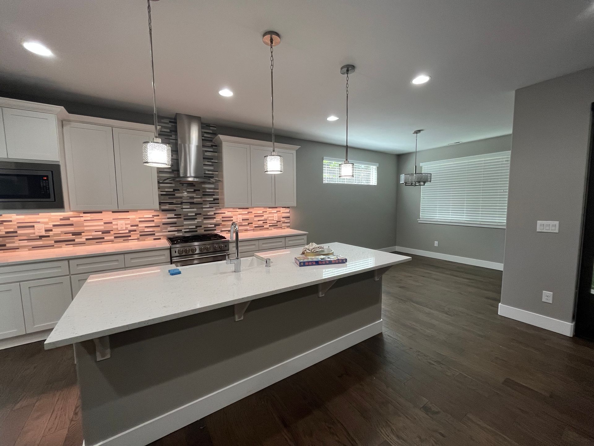Modern kitchen with island, white cabinets, stainless steel appliances, and pendant lights.