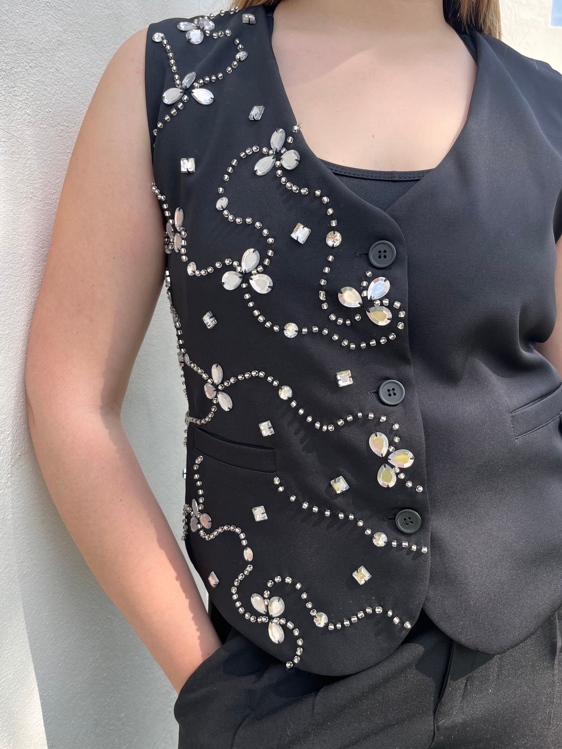 Una mujer que lleva un chaleco negro con flores blancas.