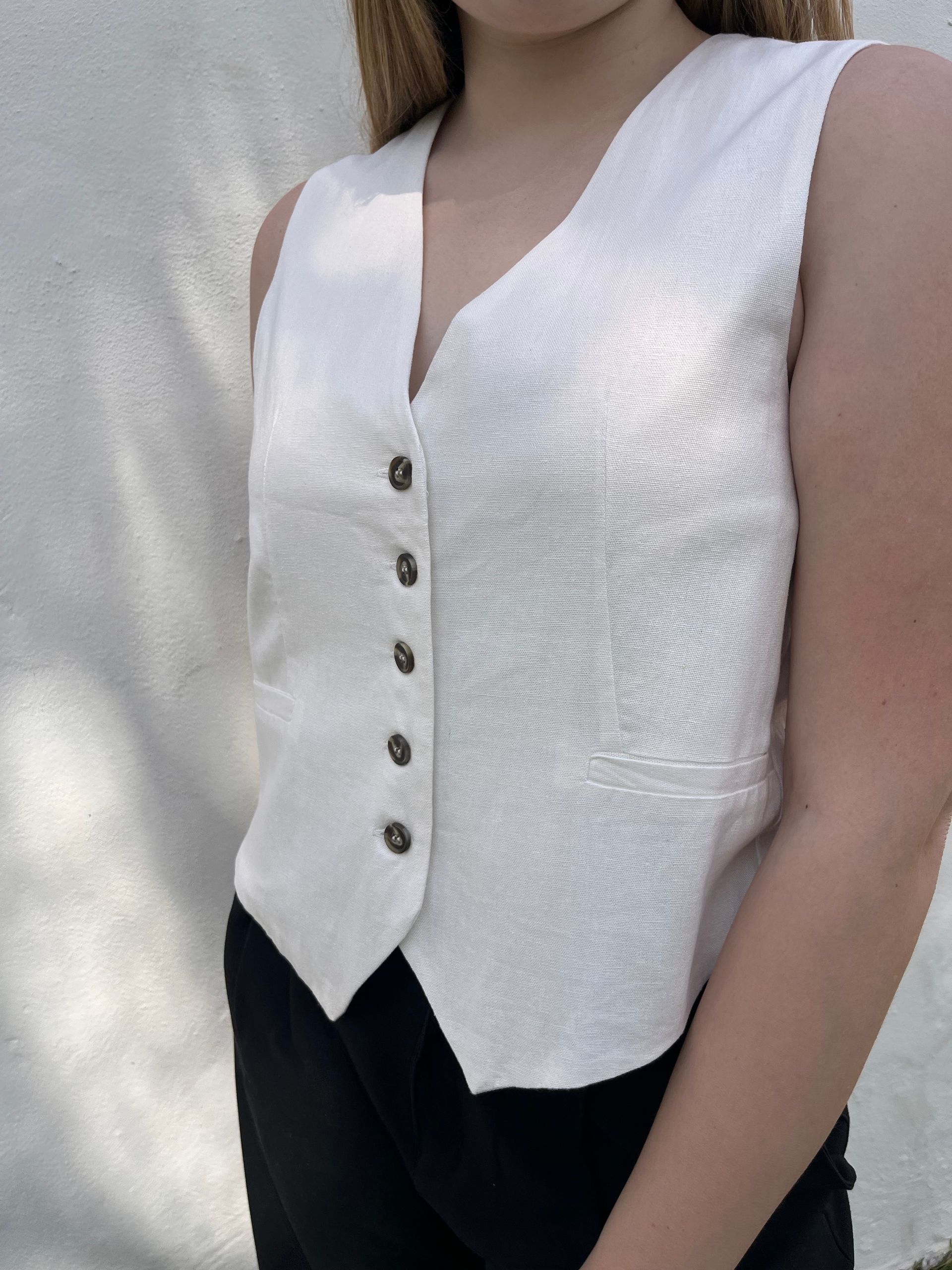 Una mujer que lleva un chaleco blanco y pantalones negros