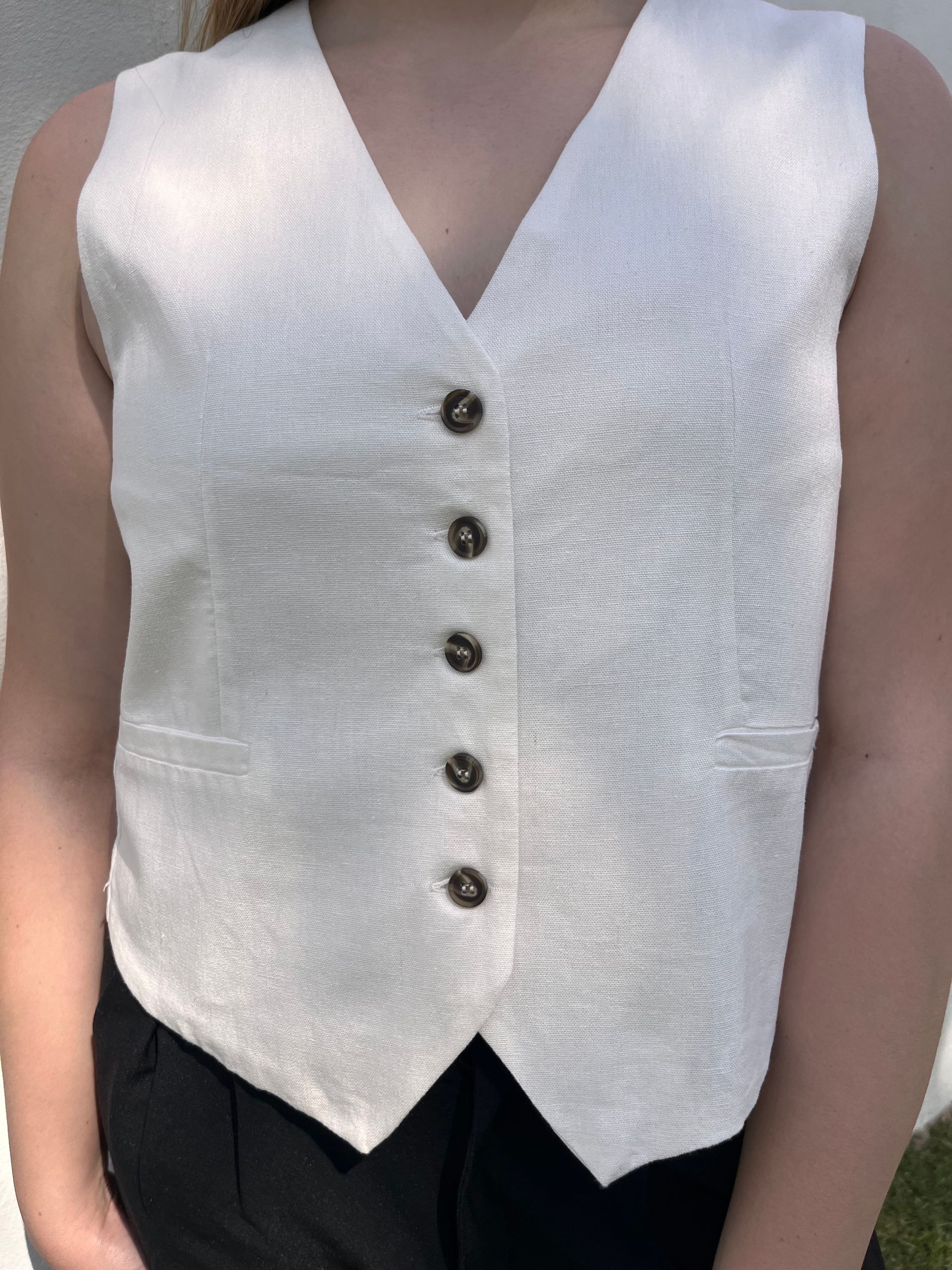 Una mujer que lleva un chaleco blanco y pantalones negros