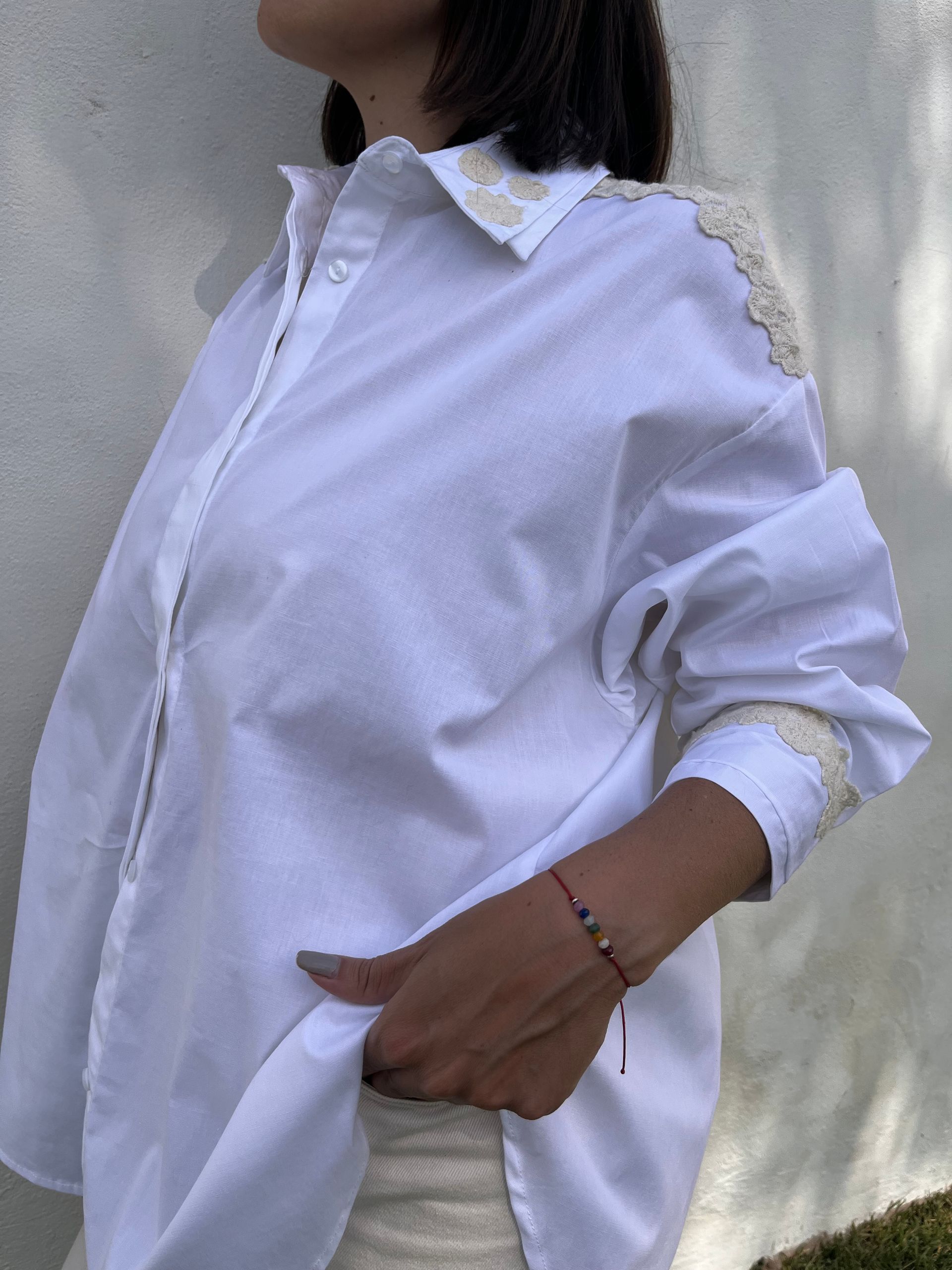 Una mujer que lleva una camisa blanca con encaje en las mangas.