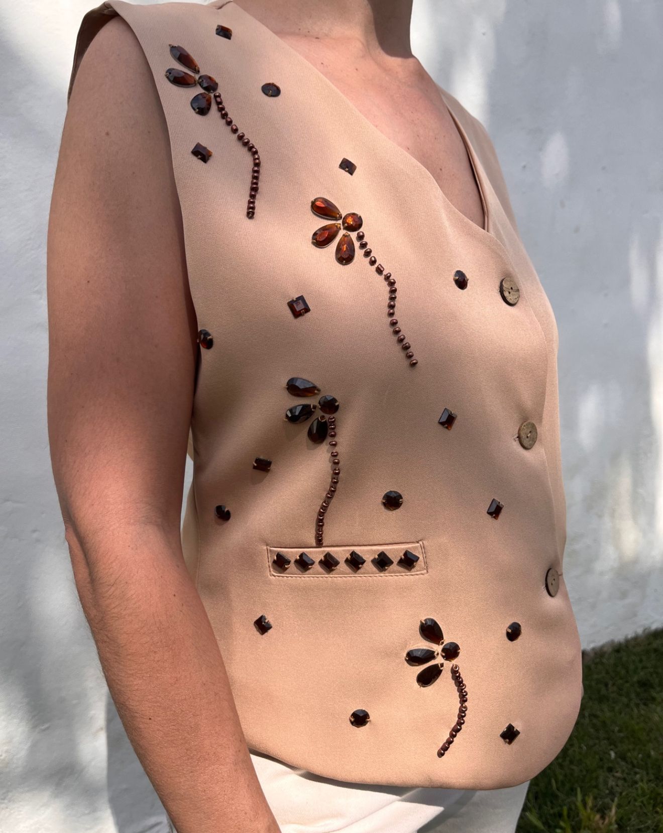 Una mujer que lleva un chaleco color canela con flores bordadas.