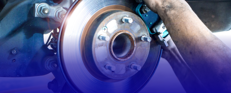 Mechanic working on a car's brake disc with blue brake caliper, close-up shot | AUTOPRO Oakville