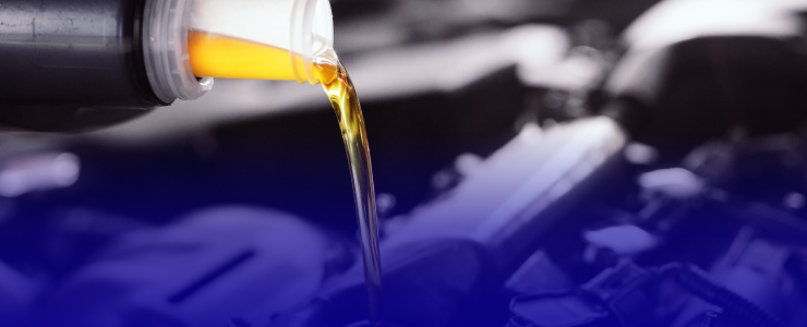 Yellow liquid pouring from a black bottle; background of engine parts, with a blue gradient | AUTOPRO Oakville