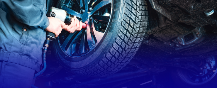 Mechanic using a pneumatic wrench on a car tire, working beneath the vehicle | AUTOPRO Oakville