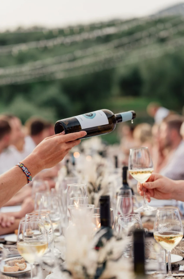 Une personne verse du vin dans un verre à une table.