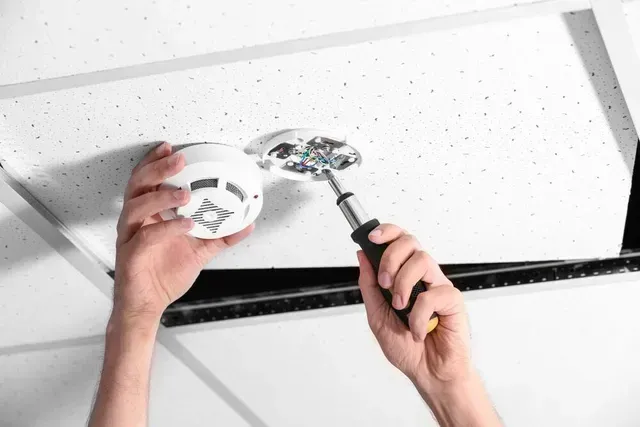 Person Installing a Smoke Detector — FNQ Smoke Alarms & Maintenance in Goldsborough, QLD