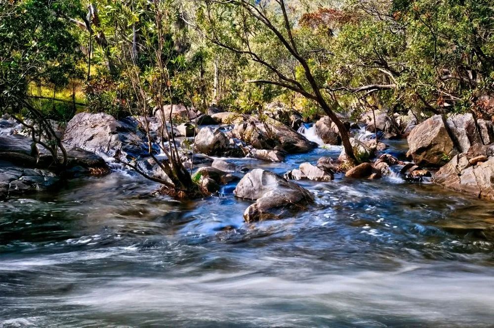 Fast-flowing Water Rushes Over Rocks in a River — FNQ Smoke Alarms & Maintenance in Mareeba, QLD