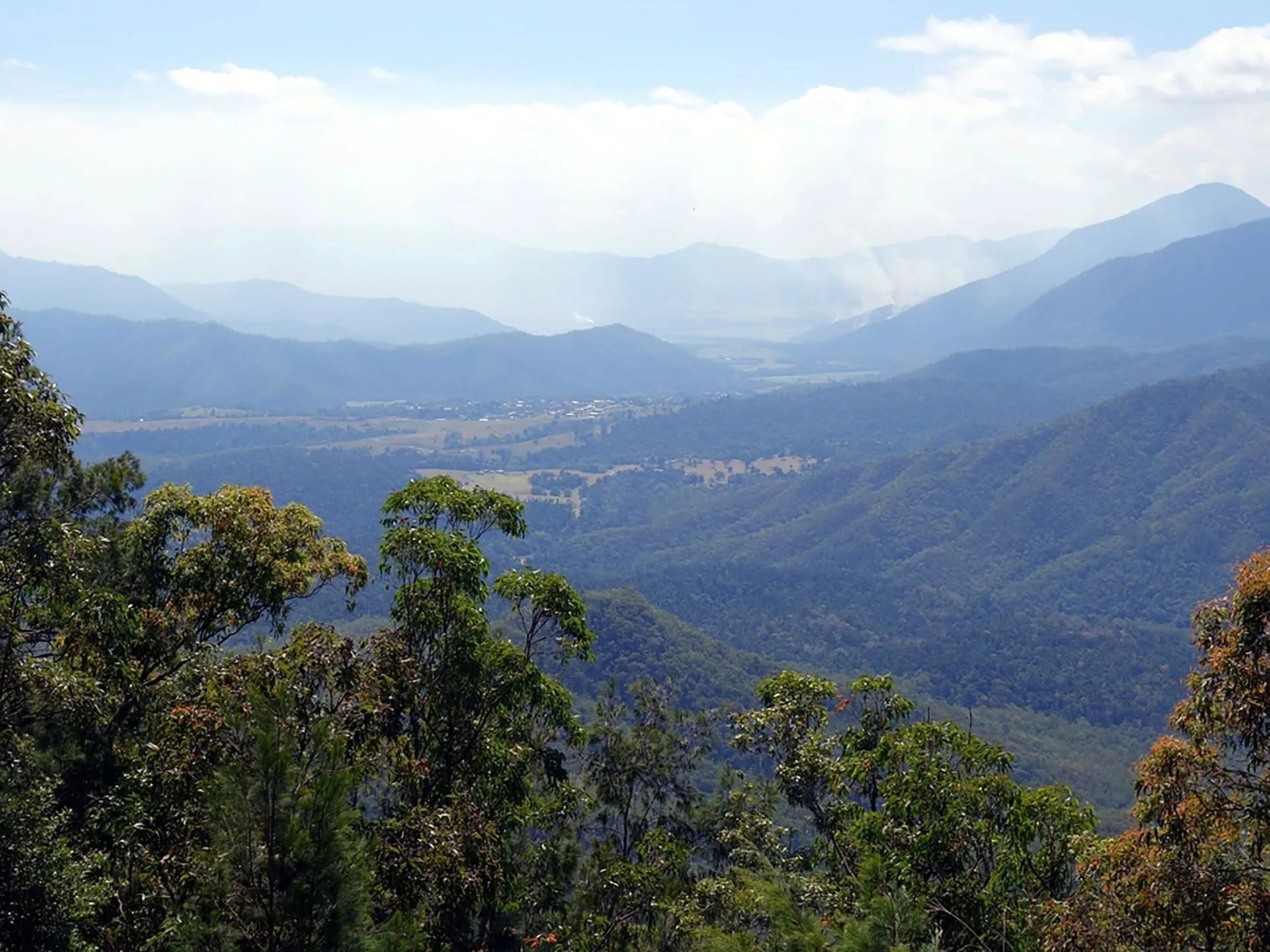 Hazy Mountain Valley With Rolling Hills, Trees in Foreground — FNQ Smoke Alarms & Maintenance in Innisfail, QLD
