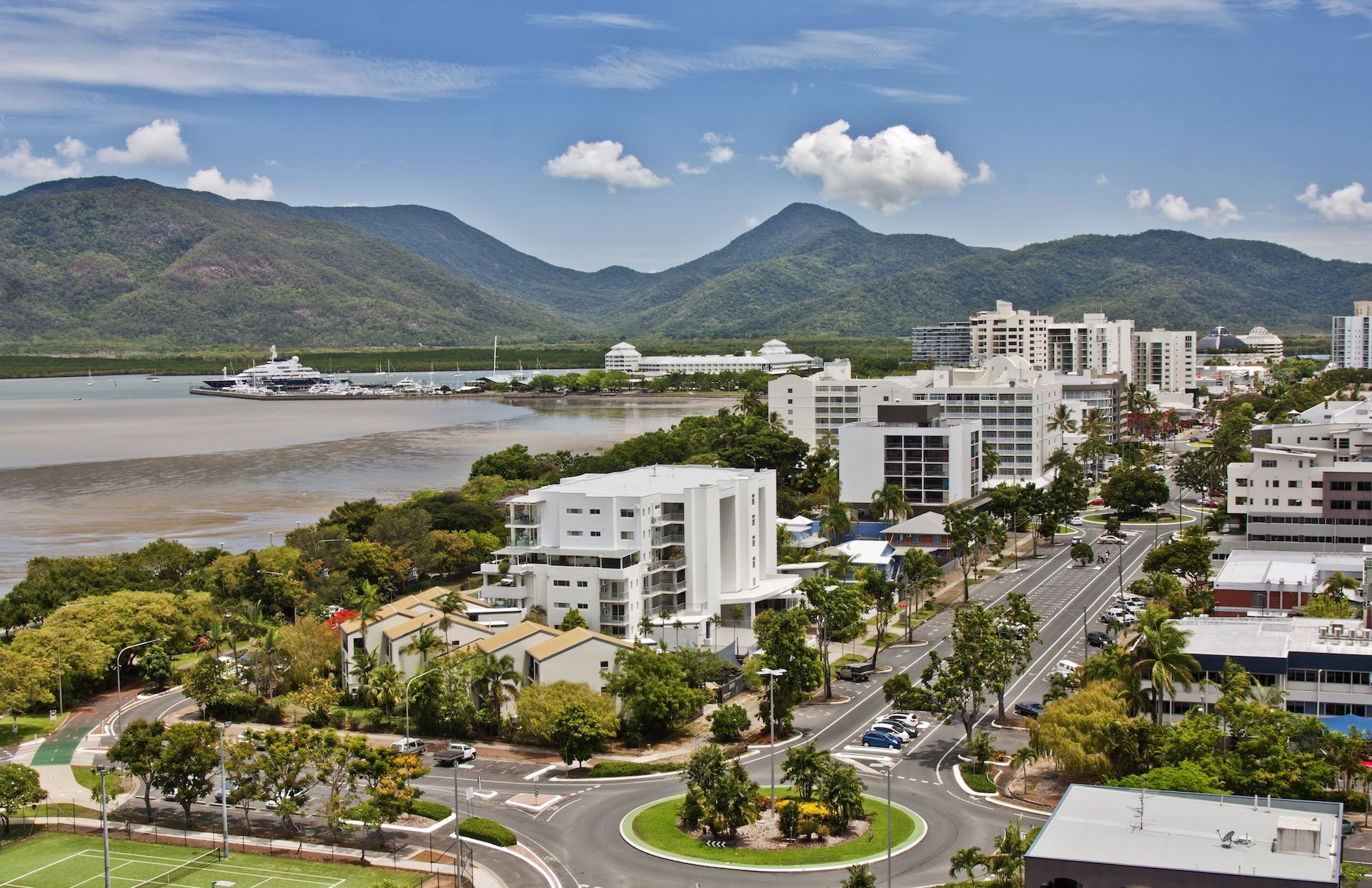 Waterfront City With Mountains in the Background Under a Blue Sky — FNQ Smoke Alarms & Maintenance in Cairns, QLD