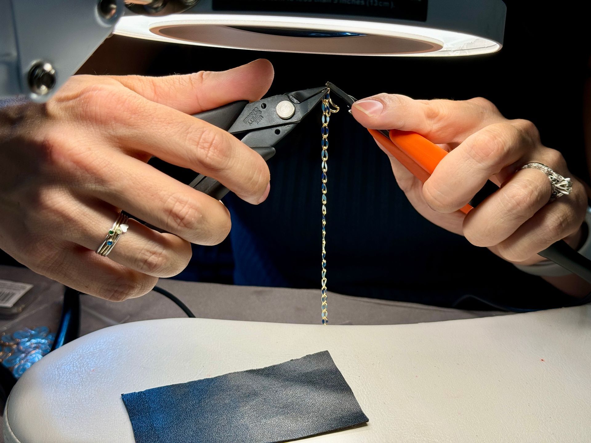 A permanent jewelry designer uses tools to make jewelry.