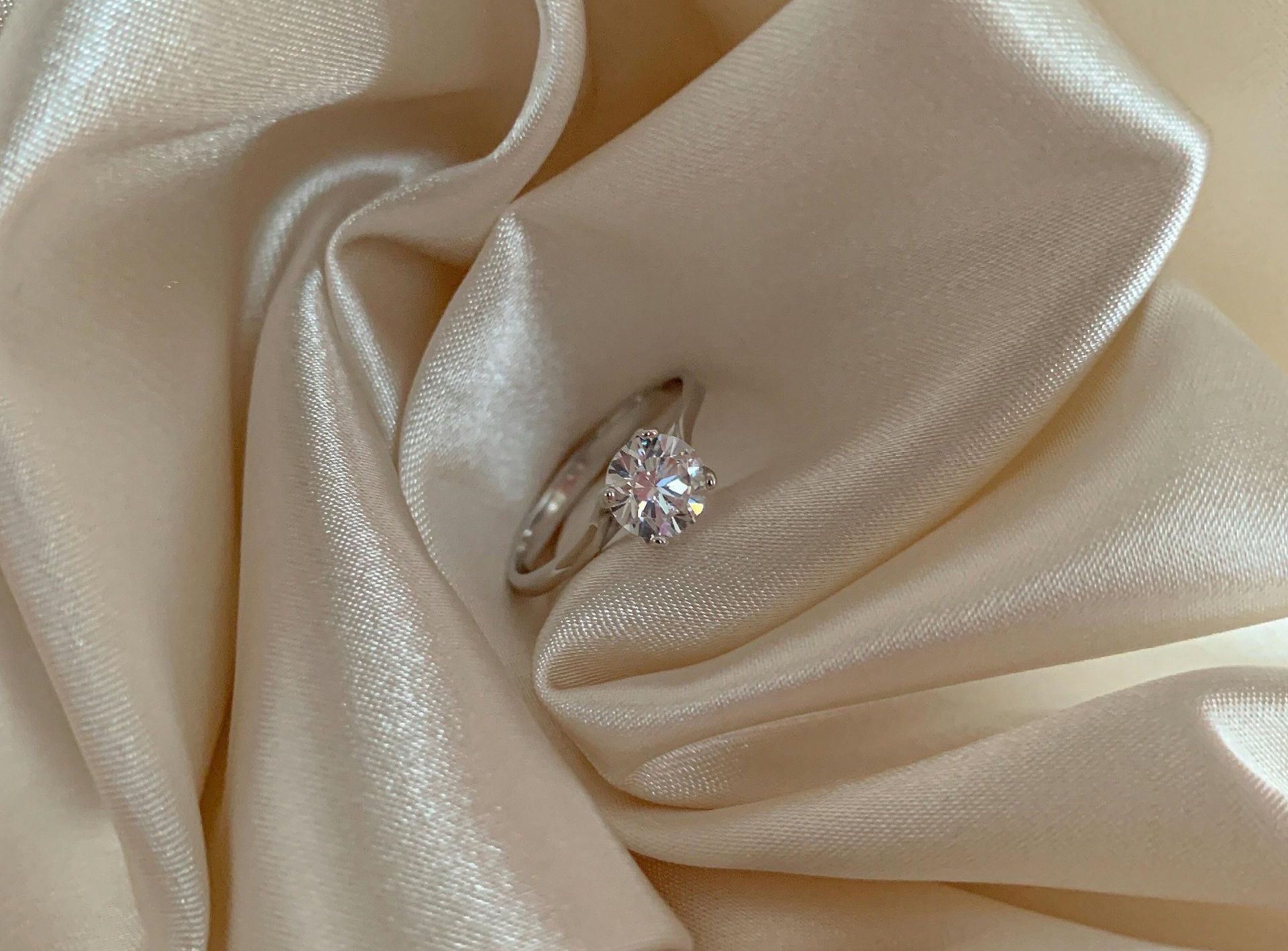 A ring with a pink stone and diamonds is sitting on a wooden surface.