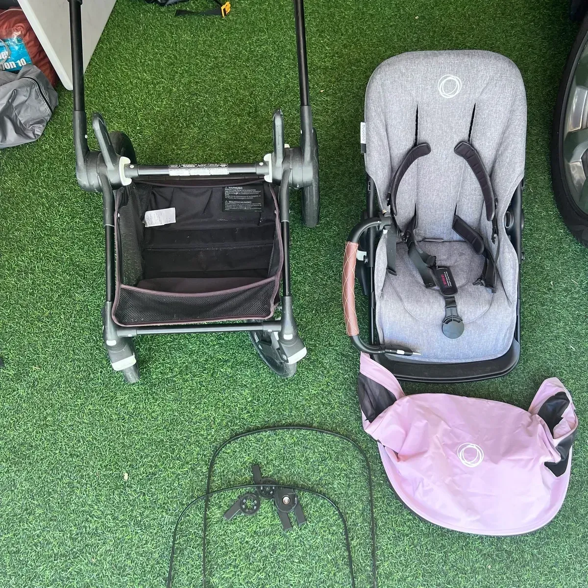 A stroller and a baby seat are sitting on the grass.
