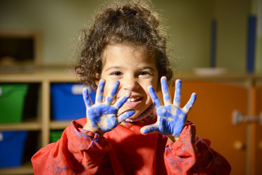 A little girl with blue paint on her hands.