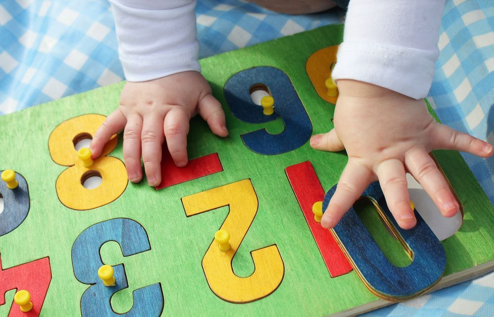 A baby is playing with a puzzle with numbers on it