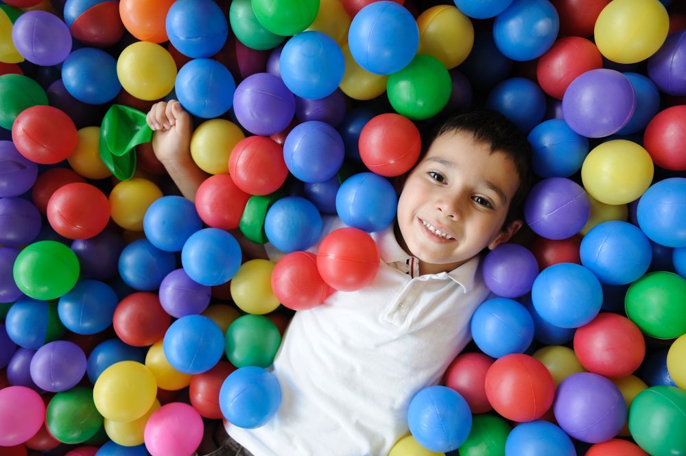 A group of children are playing with exercise balls in a gym.