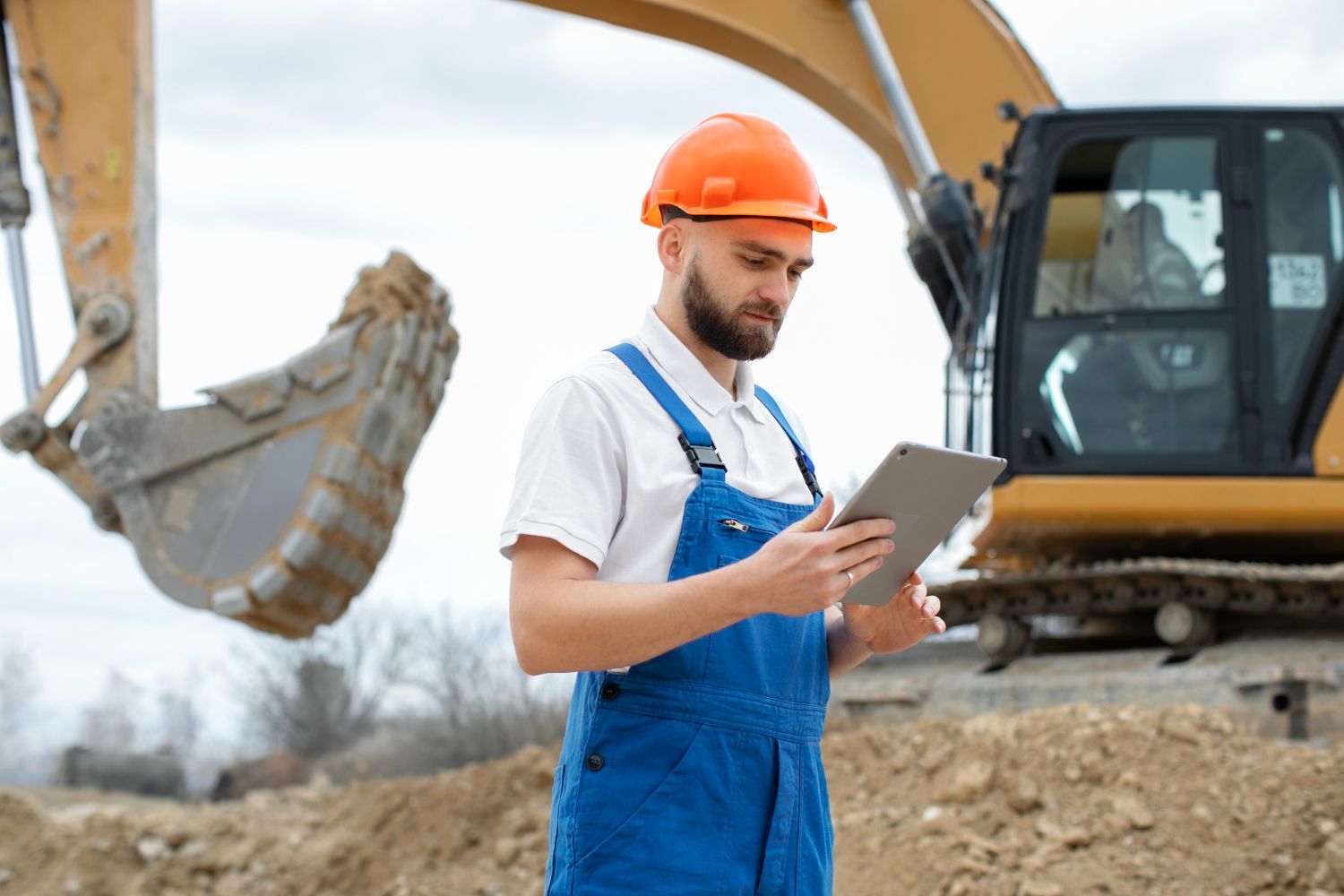 A construction worker is using a tablet computer at a construction site.