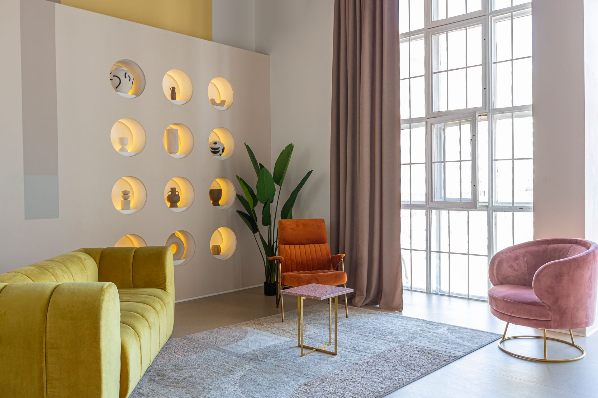 A living room with a yellow couch , pink chair , and a table.