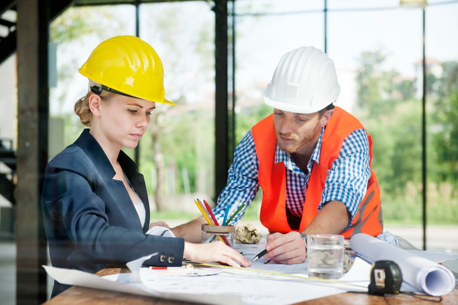 A man and a woman are sitting at a table looking at a blueprint.