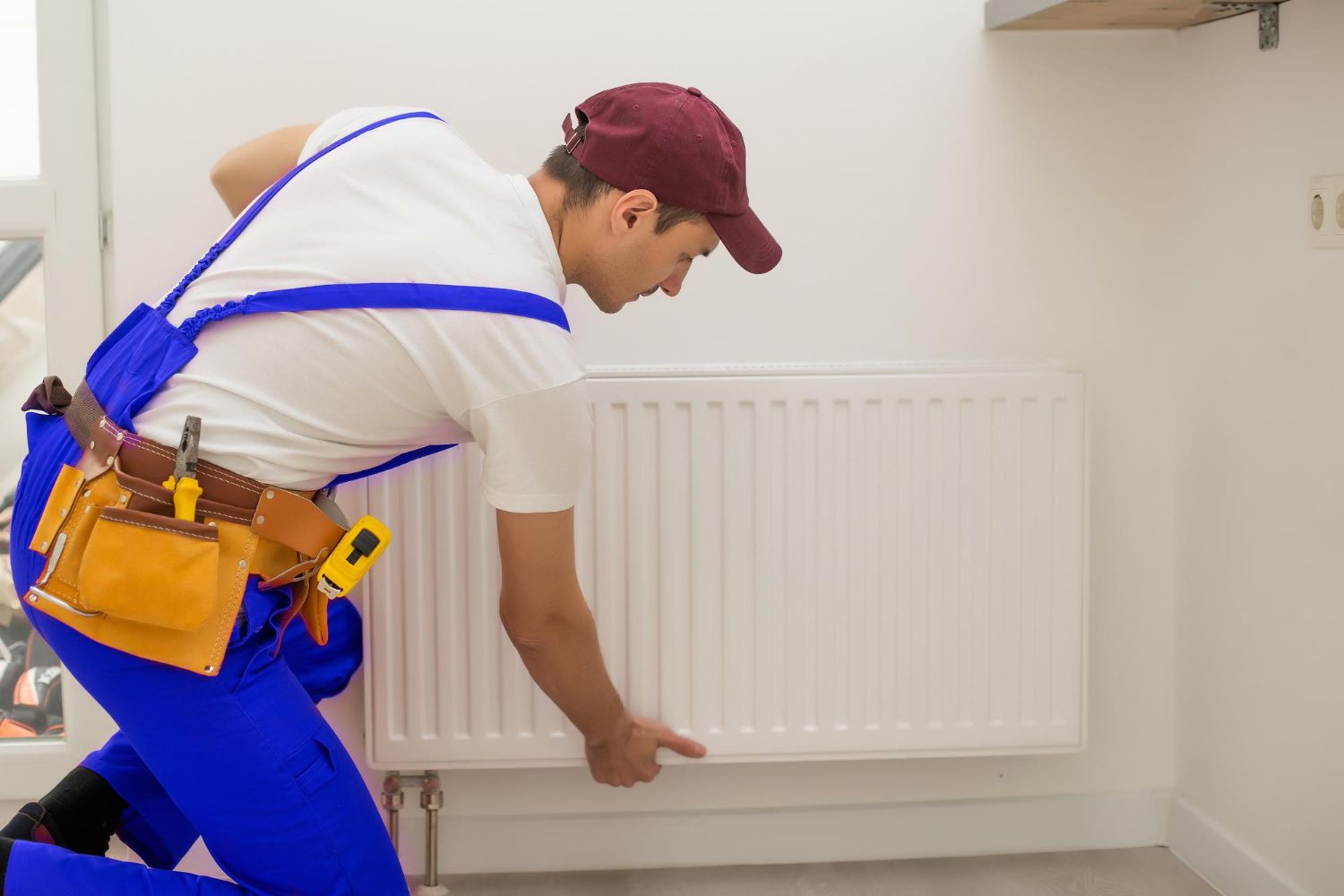 A man is working on a radiator in a room.