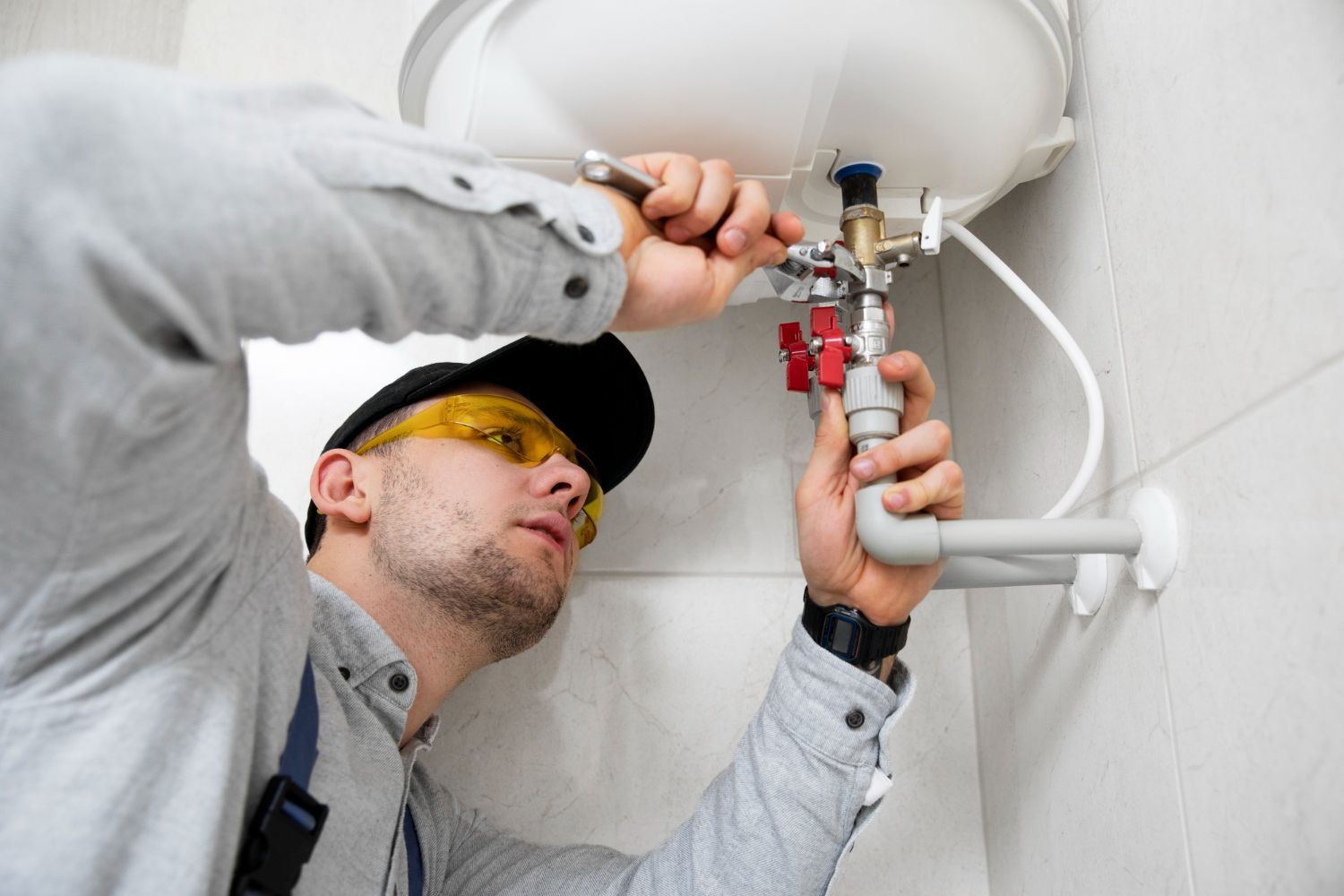 A man is fixing a water heater in a bathroom.