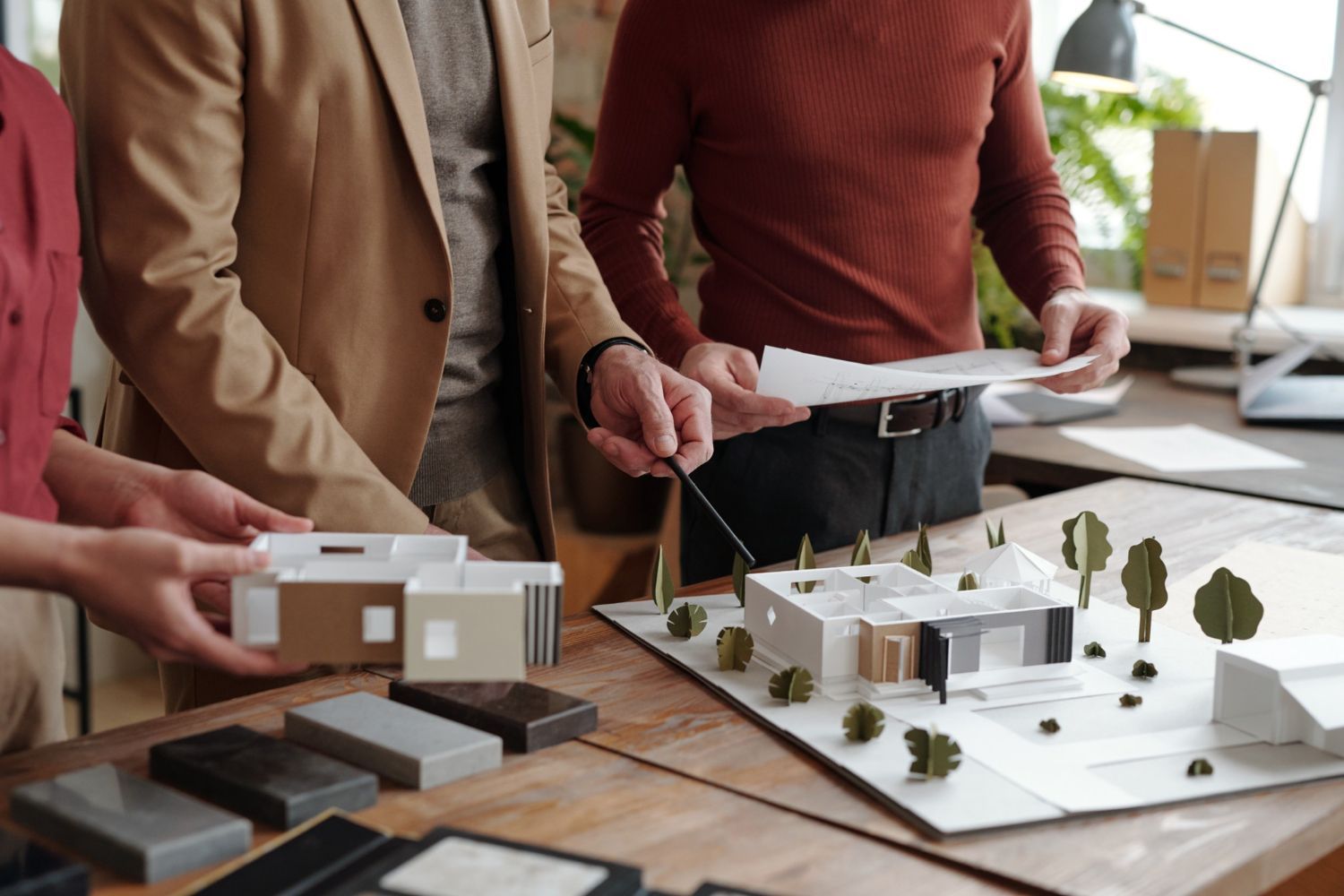 A group of people are looking at a model of a house on a table.