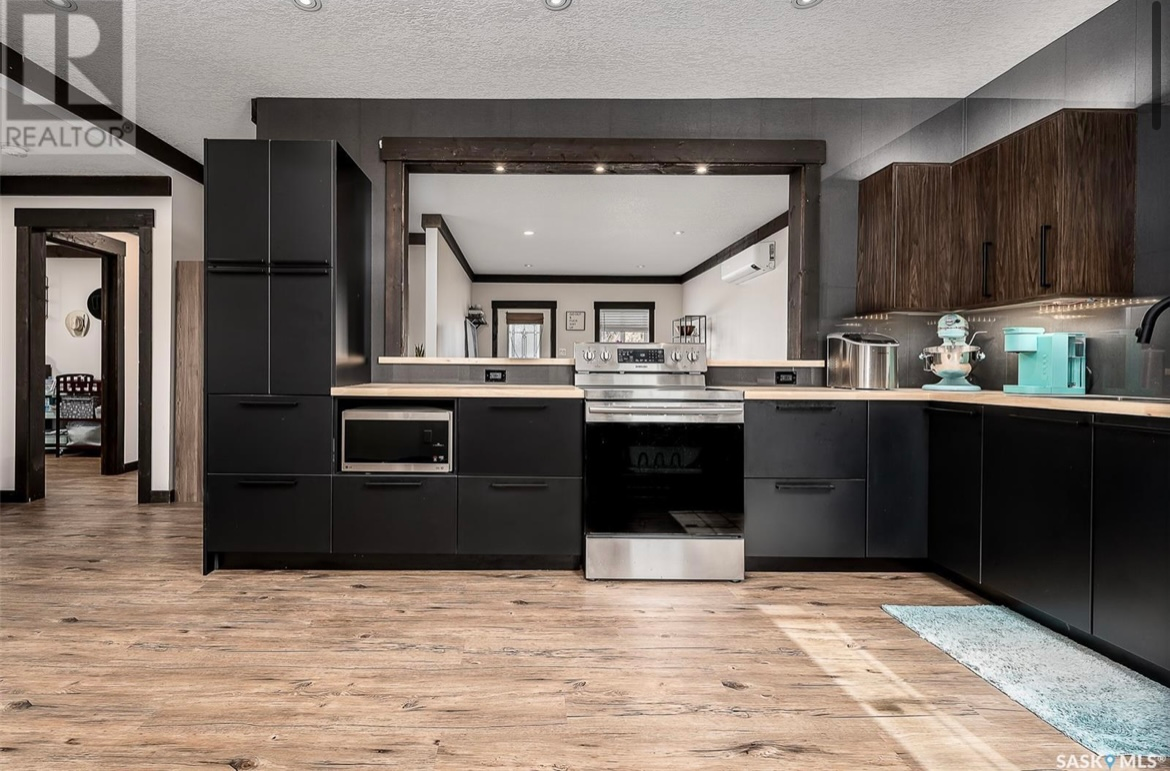 A kitchen with black cabinets , stainless steel appliances , and wooden floors.