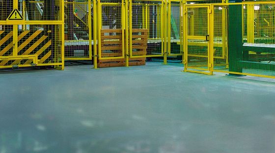 Un magazzino con un sacco di recinzioni gialle e pallet sul pavimento.