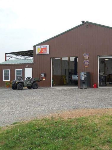 Brown building with open garage doors; an ATV parked out front.
