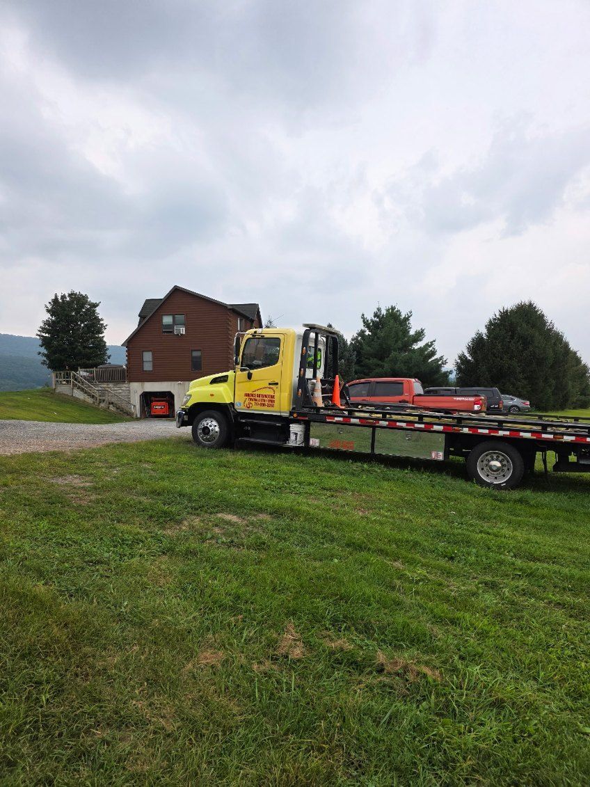 Yellow tow truck parked on a grassy area in front of a house. Cloudy sky.