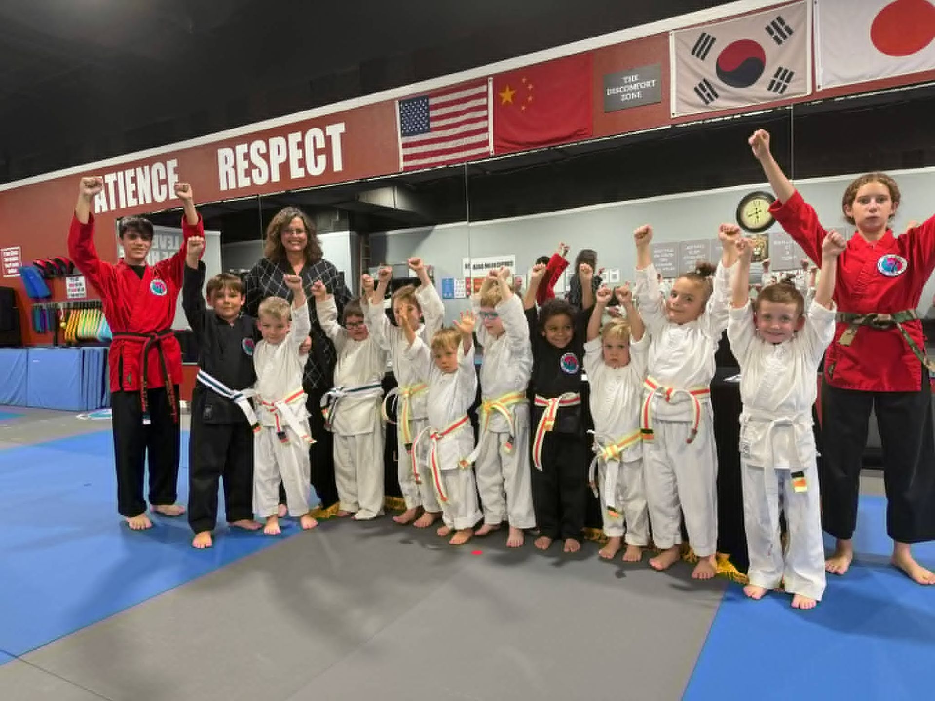 A group of young children in karate uniforms are posing for a picture.
