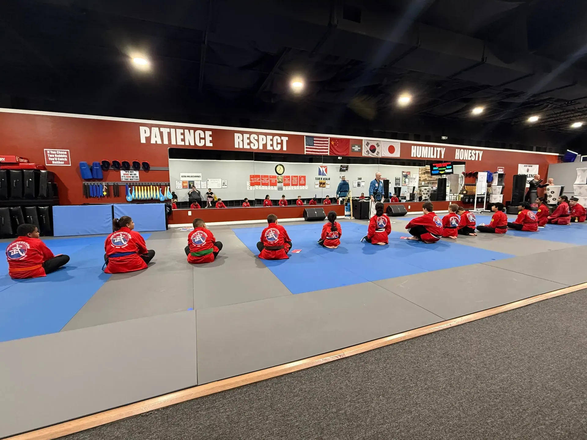 Indoor go-kart track with red karts lined up on a blue floor under a sign reading “PRACTICE READY!”