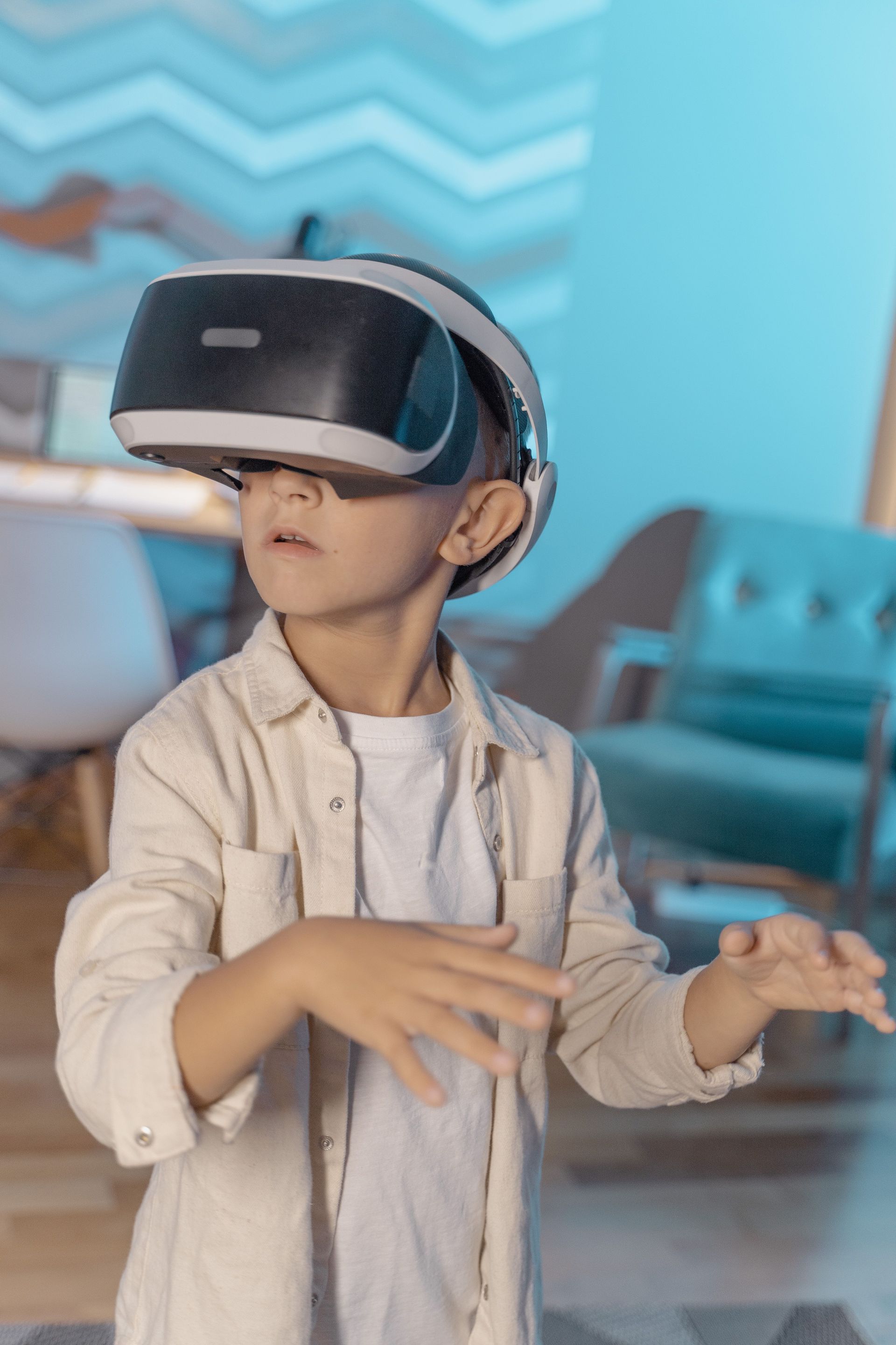 Child wearing a VR headset with hands raised in a bright modern room
