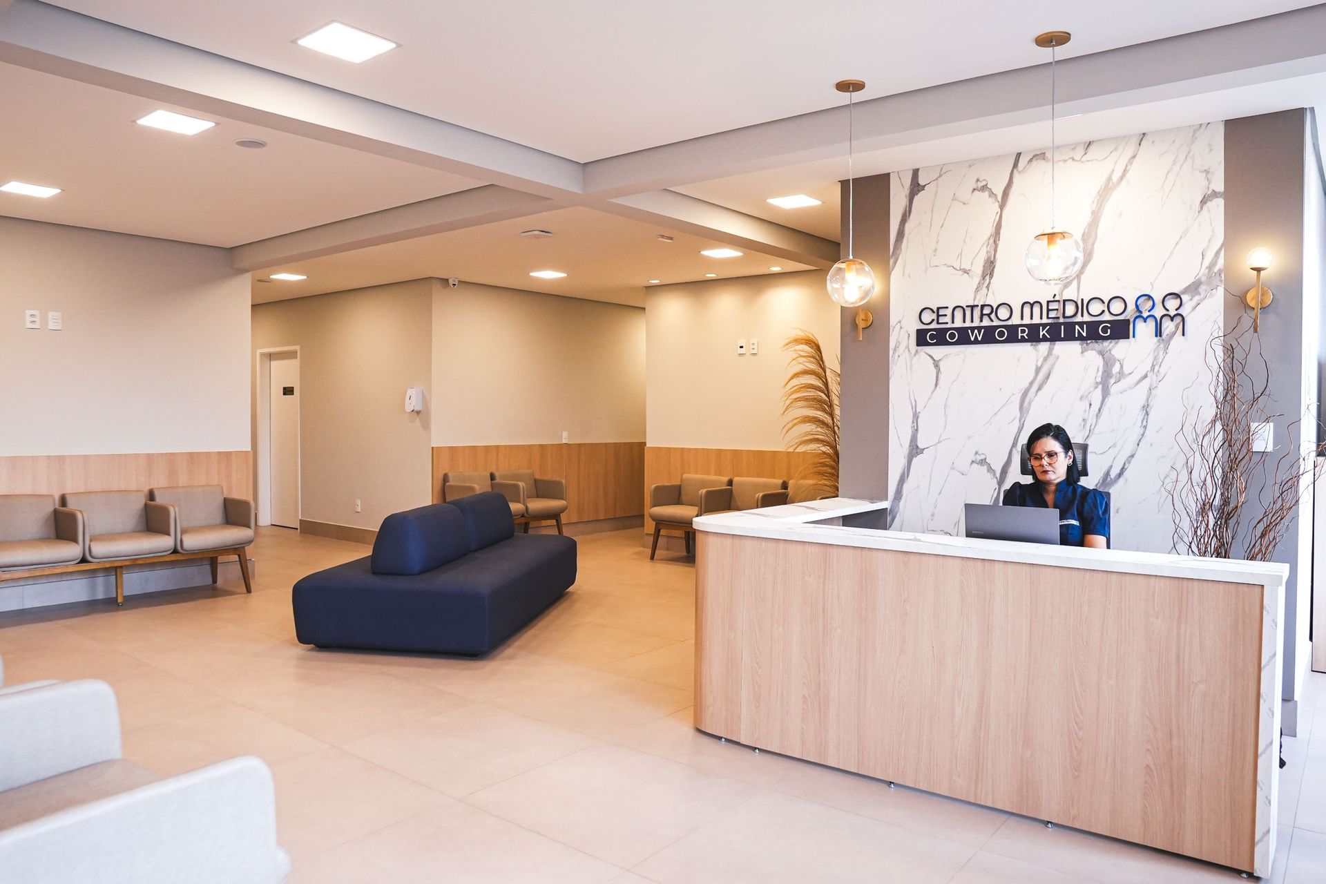 Uma mulher está sentada à mesa com um livro e uma xícara de café.