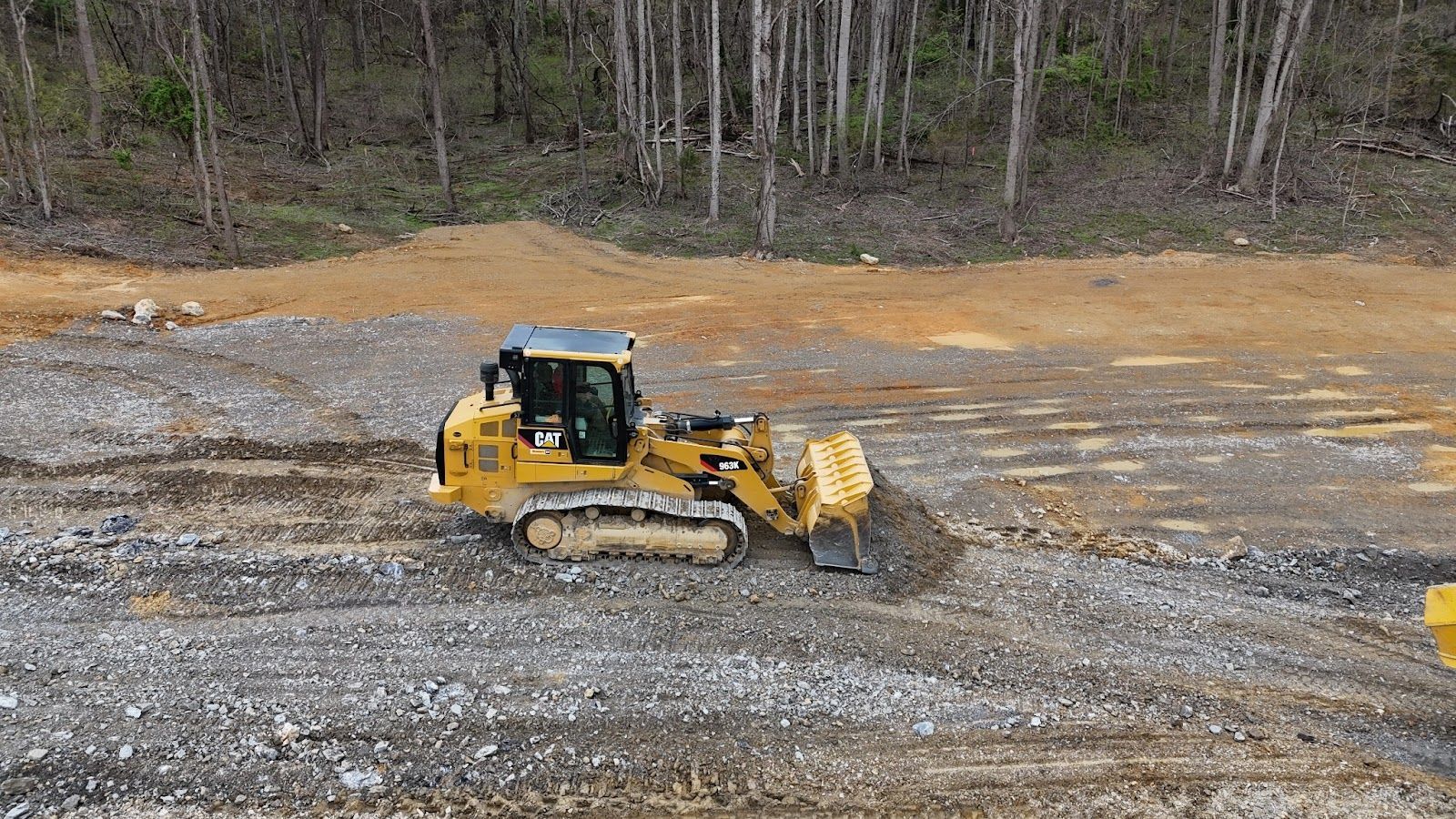 A bulldozer is driving through a dirt field.